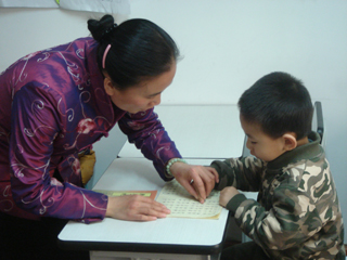 老师在指导小朋友用手指指字读经